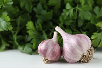 Photo of Fresh raw garlic and parsley on white wooden table, closeup