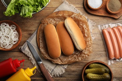 Different tasty ingredients for hot dog on wooden table, flat lay