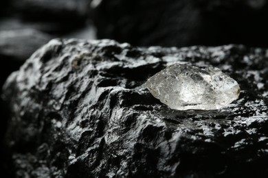 Photo of Shiny rough diamond on stone surface, closeup. Space for text