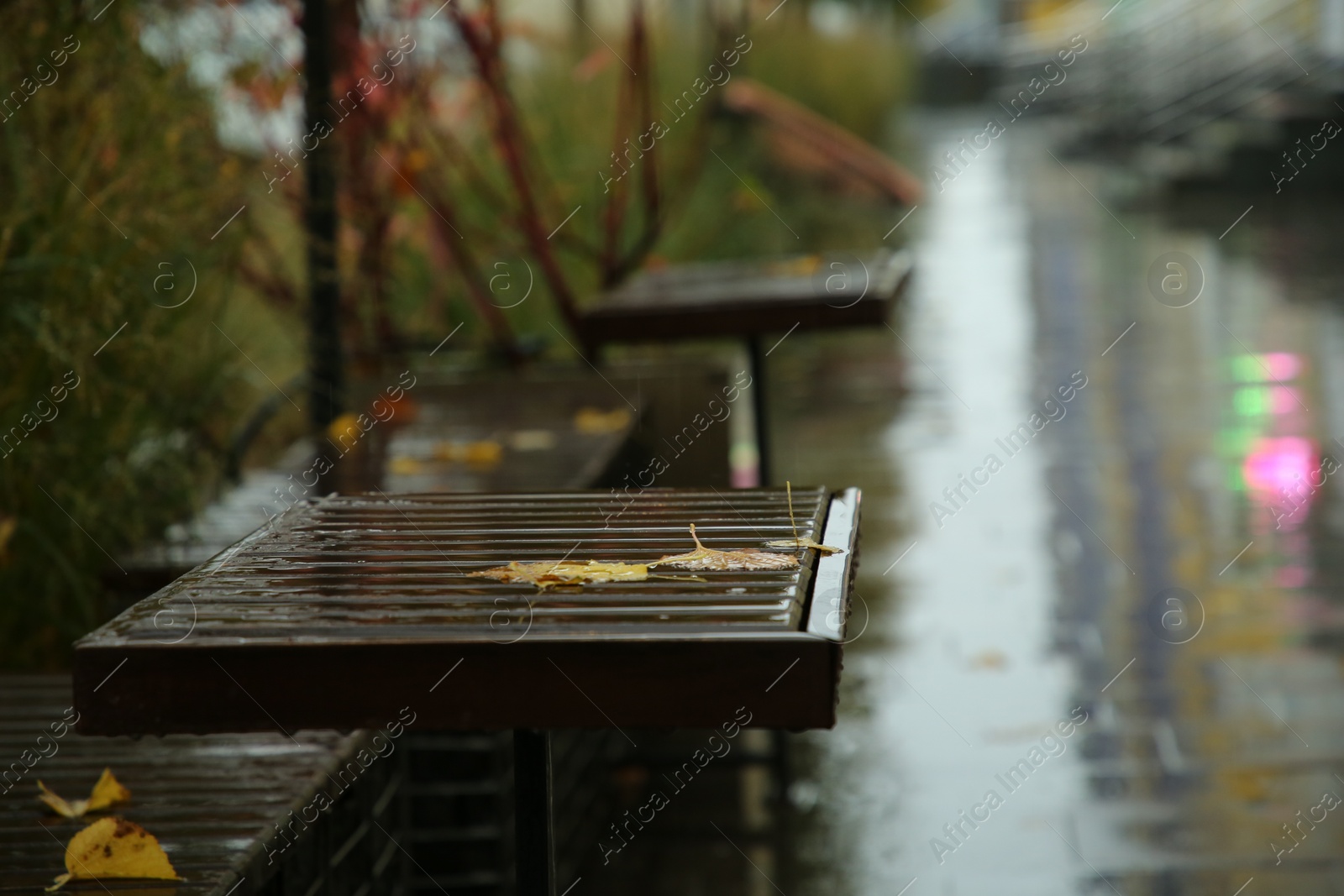 Photo of Wet tables and benches on city street after rain