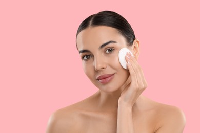 Photo of Beautiful woman removing makeup with cotton pad on pink background. Space for text