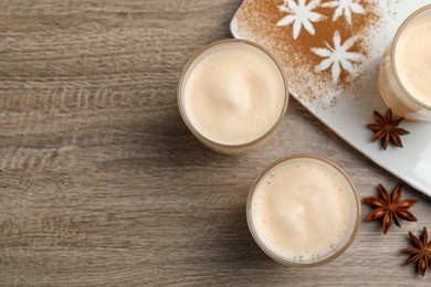 Photo of Delicious eggnog with anise on wooden table, flat lay. Space for text