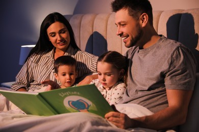 Photo of Family reading book together in bed at home