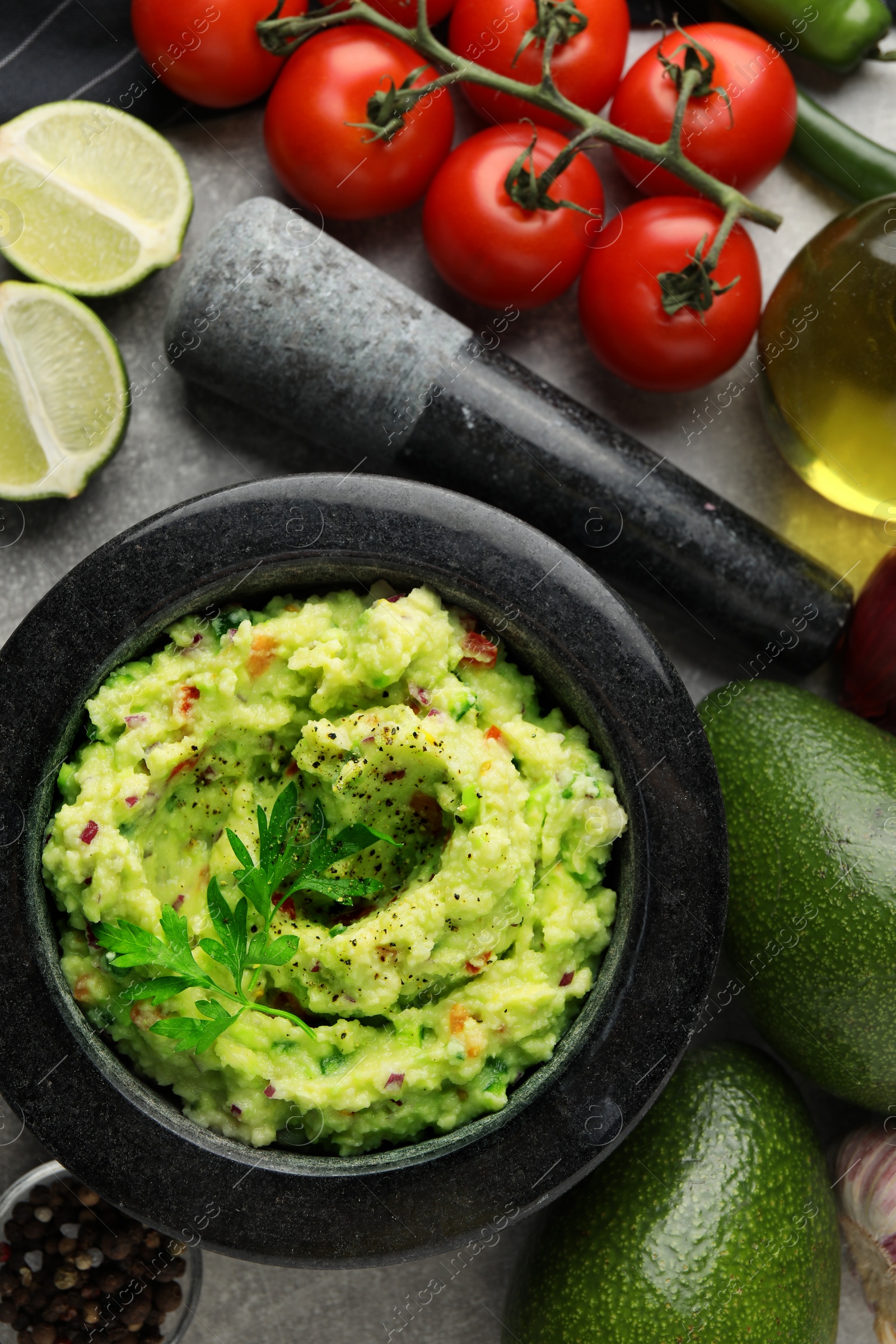 Photo of Delicious guacamole and ingredients on grey table, flat lay