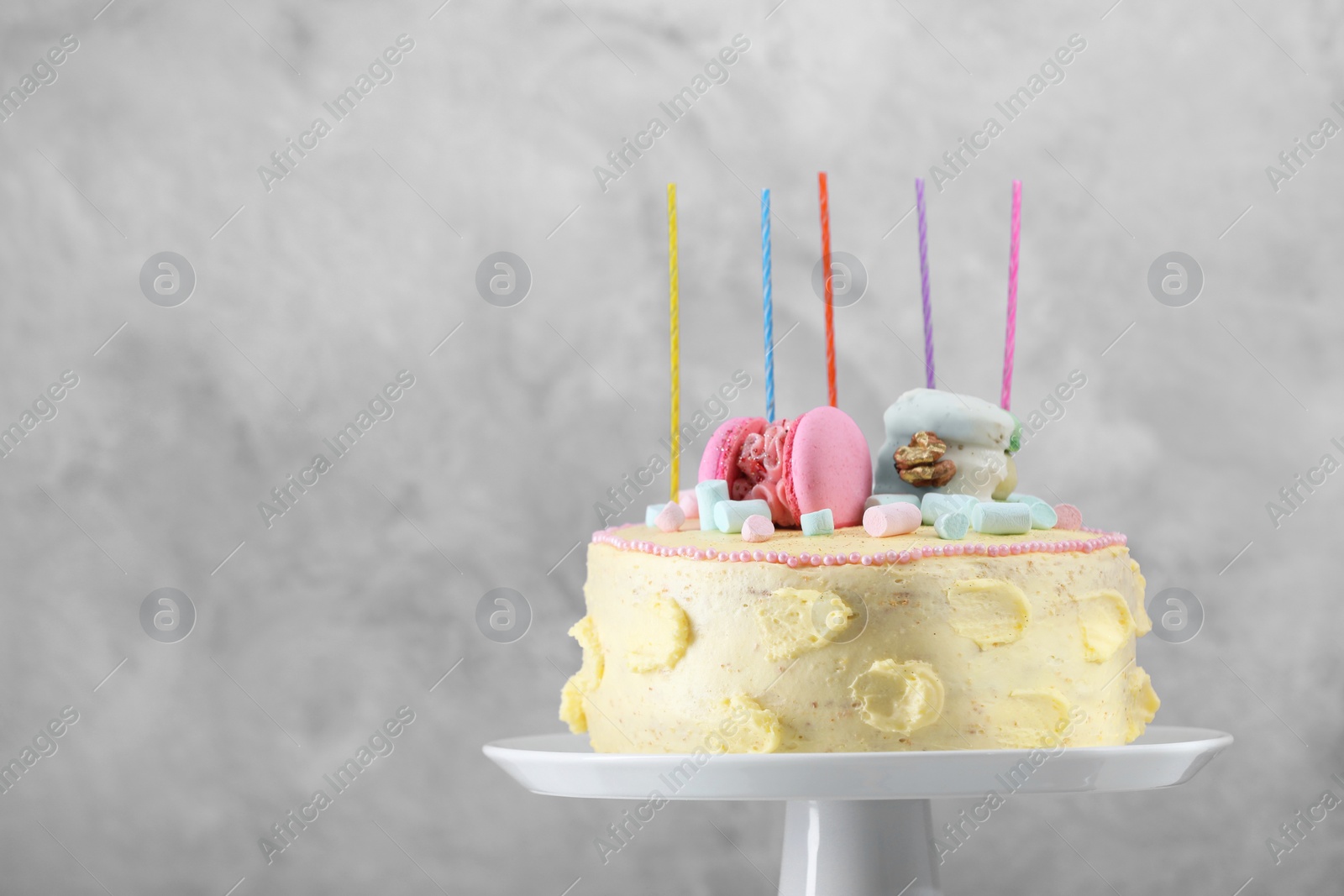 Photo of Delicious cake decorated with macarons and marshmallows against grey background, space for text