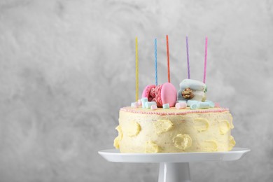 Photo of Delicious cake decorated with macarons and marshmallows against grey background, space for text