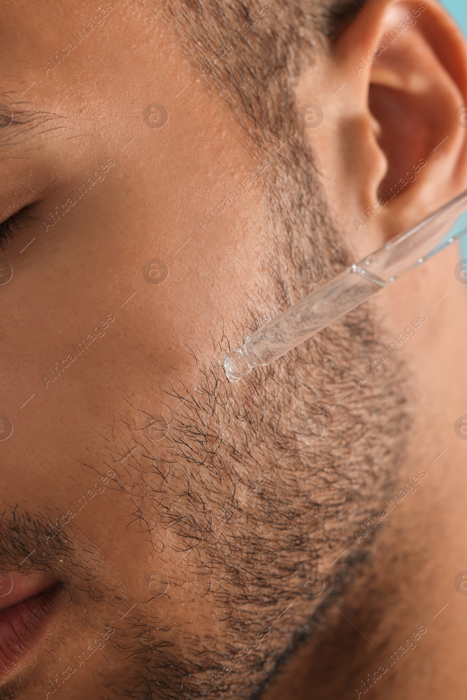 Photo of Man applying cosmetic serum onto face, closeup