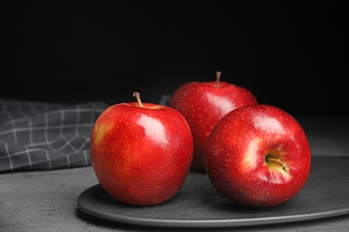 Photo of Board with ripe juicy red apples on grey table