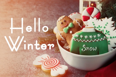Image of Greeting card with text Hello winter. Delicious Christmas cookies in bowl on grey table