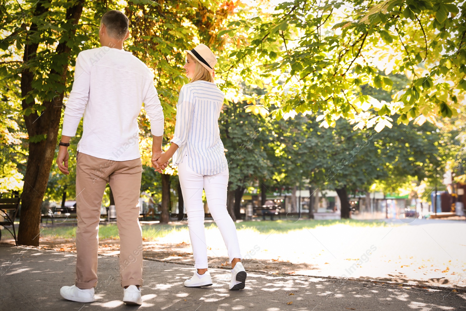 Photo of Happy couple walking along park on summer day