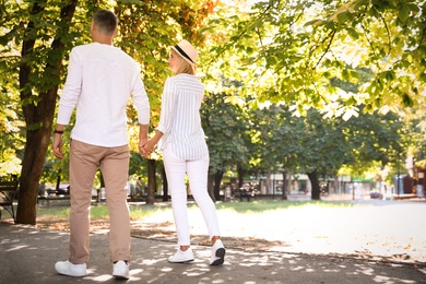 Happy couple walking along park on summer day