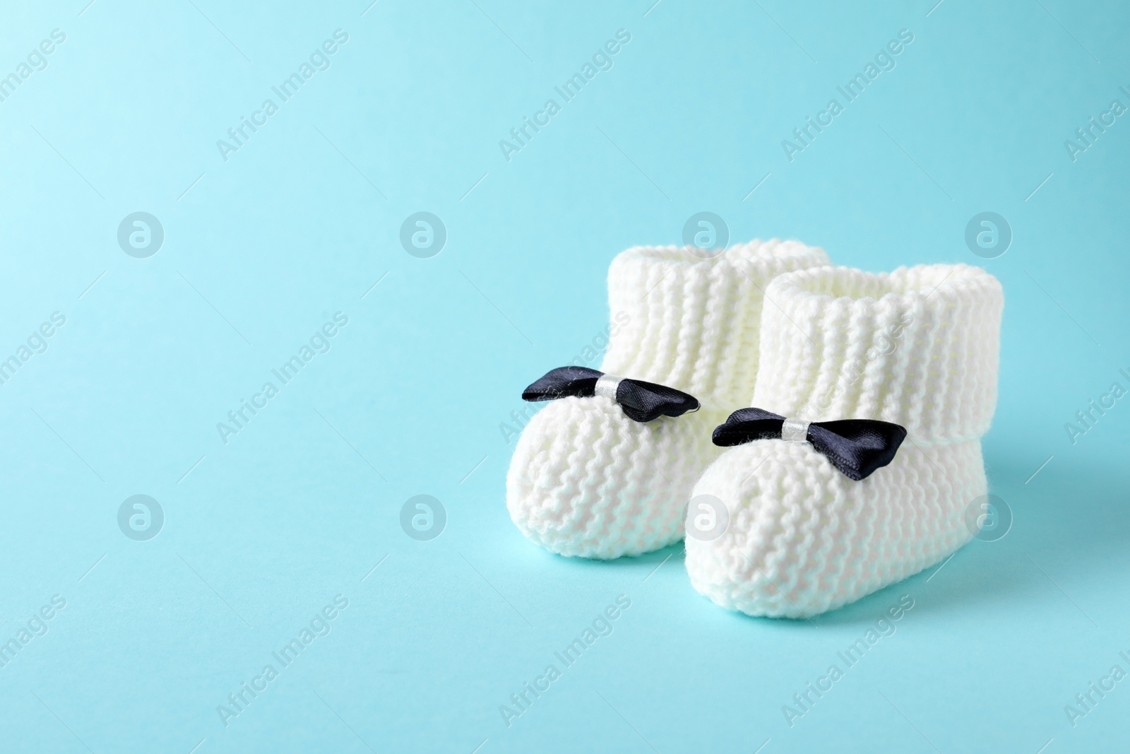 Photo of Handmade baby booties on color background. Space for text