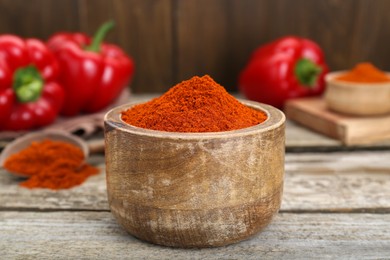 Photo of Bowl with aromatic paprika powder on old wooden table