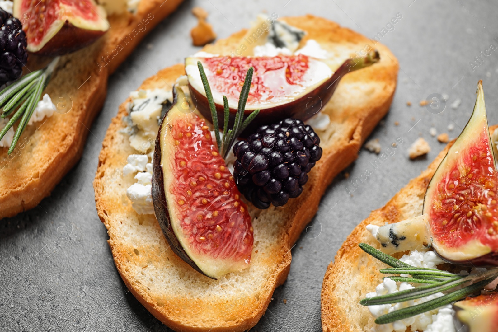 Photo of Bruschettas with cheese, figs and blackberries on grey table, closeup