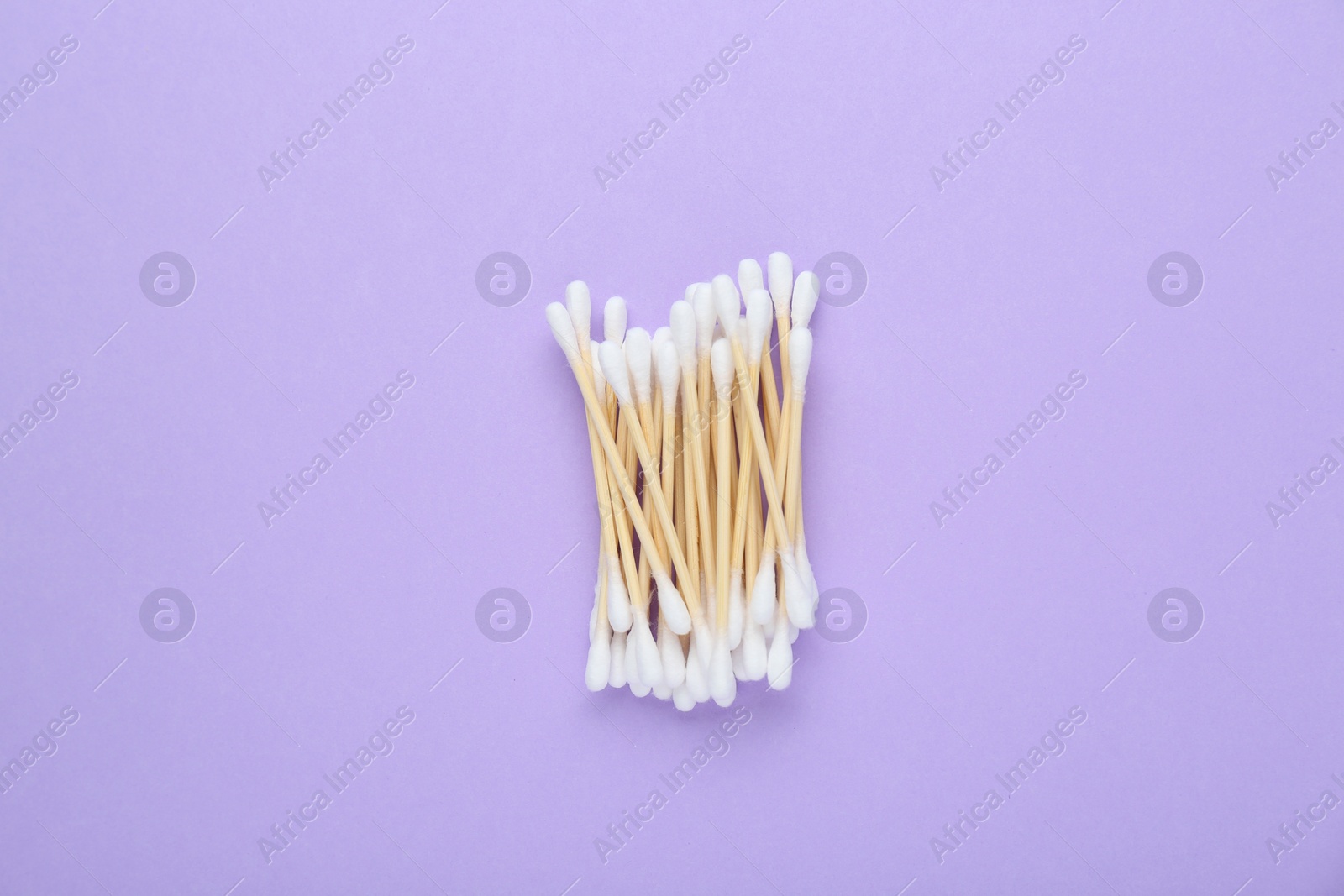 Photo of Wooden cotton buds on violet background, flat lay