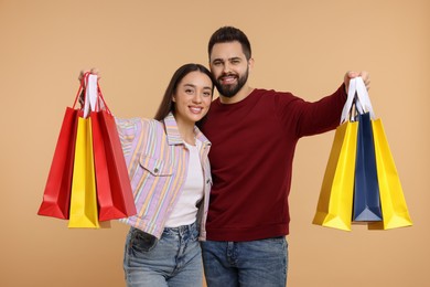 Photo of Happy couple with shopping bags on beige background