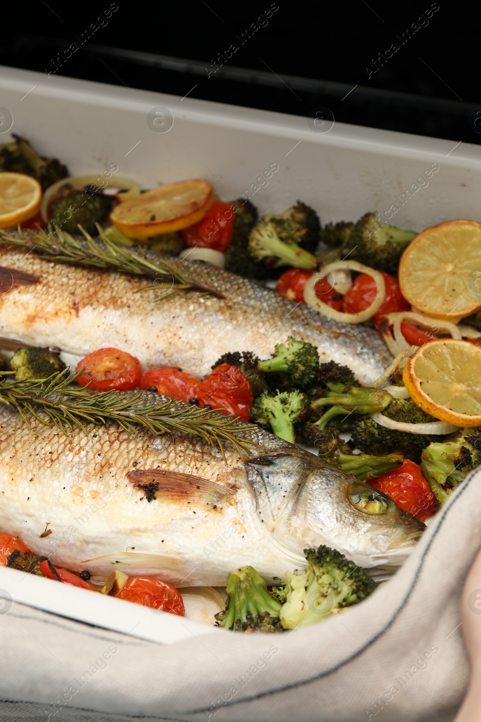 Photo of Delicious fish with vegetables and lemon in baking dish, closeup