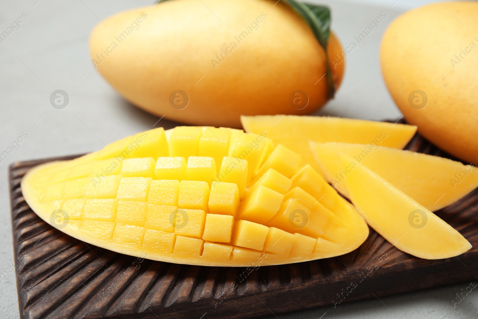 Photo of Ripe juicy mango on grey table, closeup