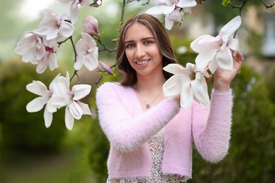 Beautiful young woman near blossoming magnolia tree on spring day