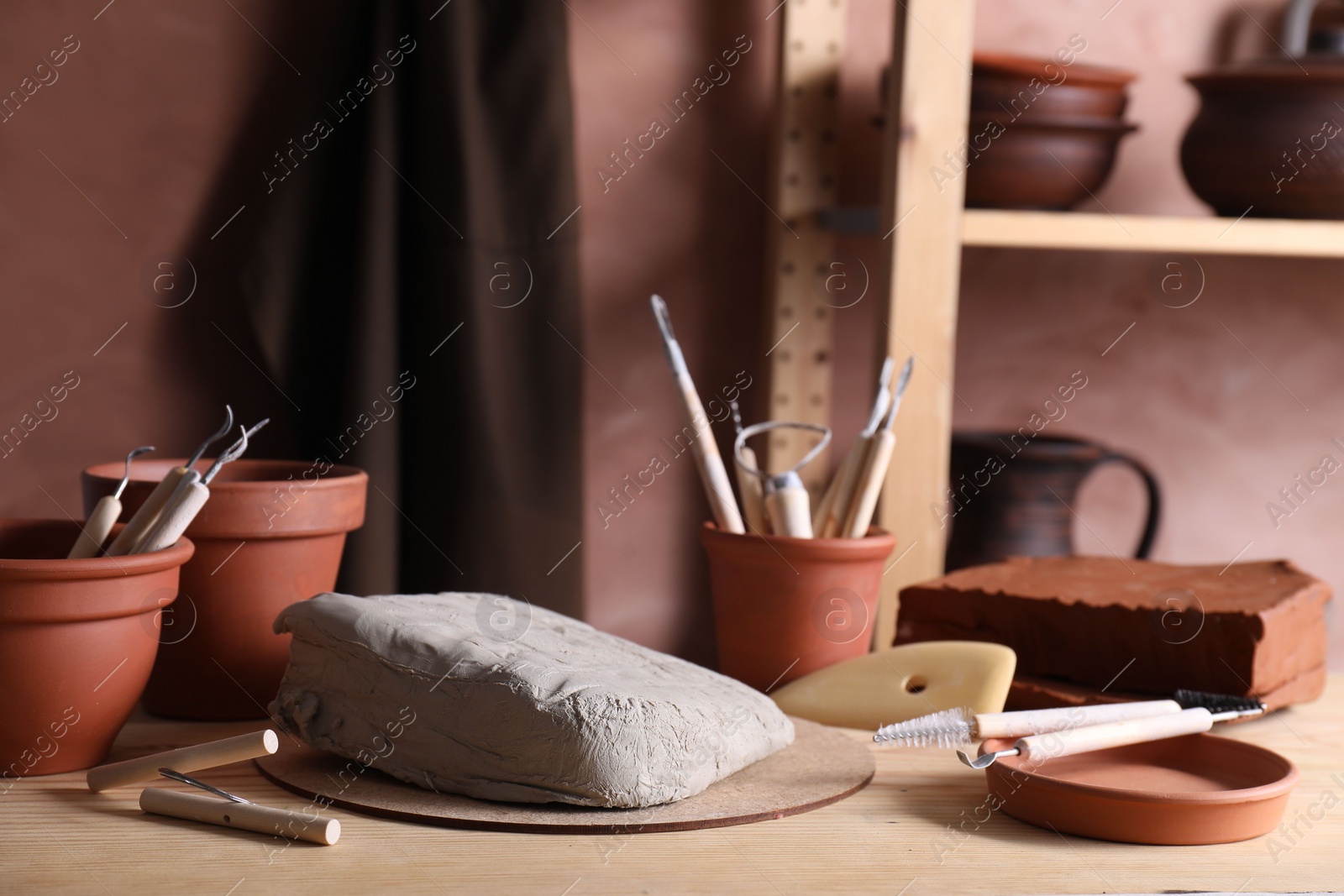 Photo of Clay and set of modeling tools on wooden table in workshop