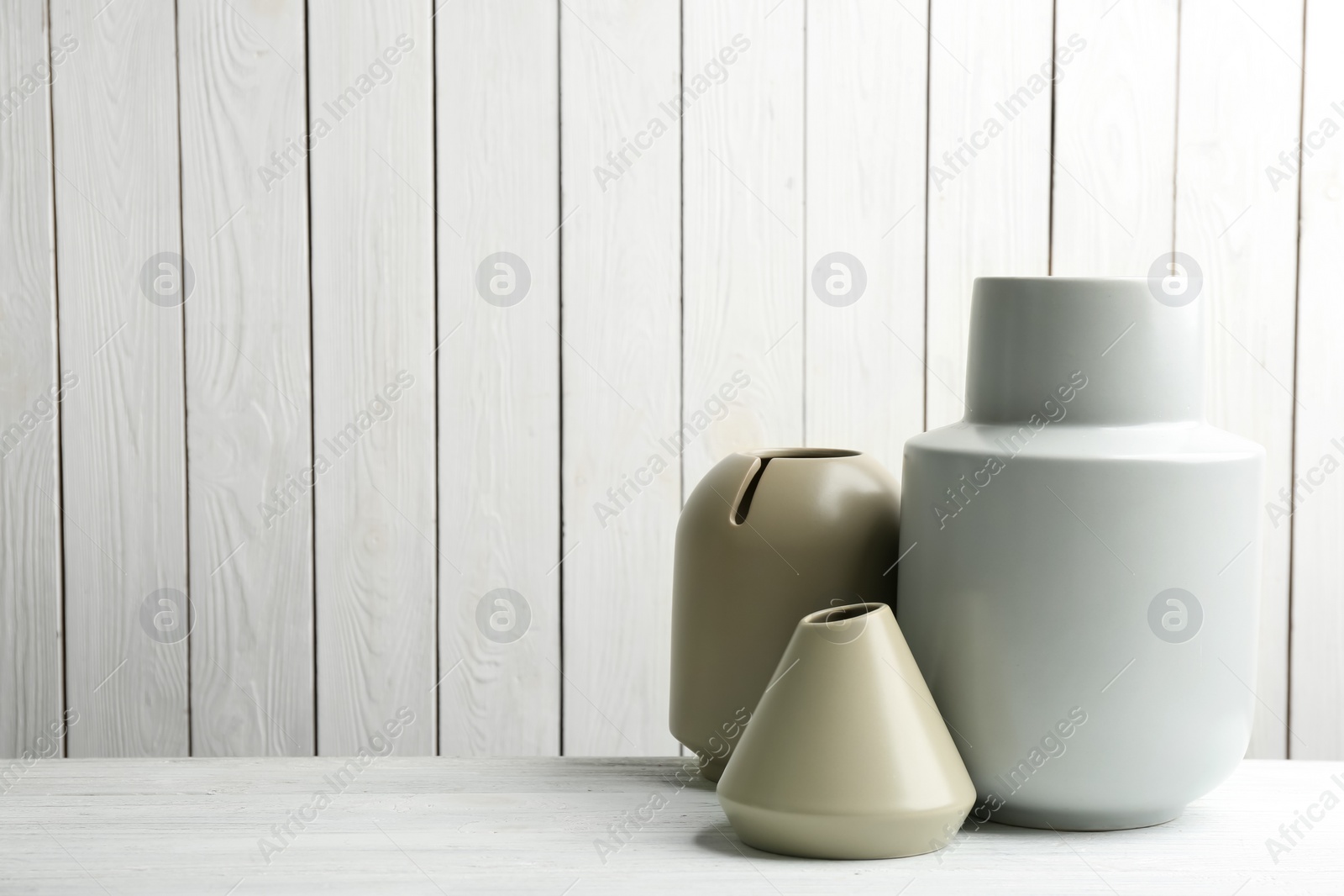 Photo of Stylish ceramic vases on white wooden table. Space for text