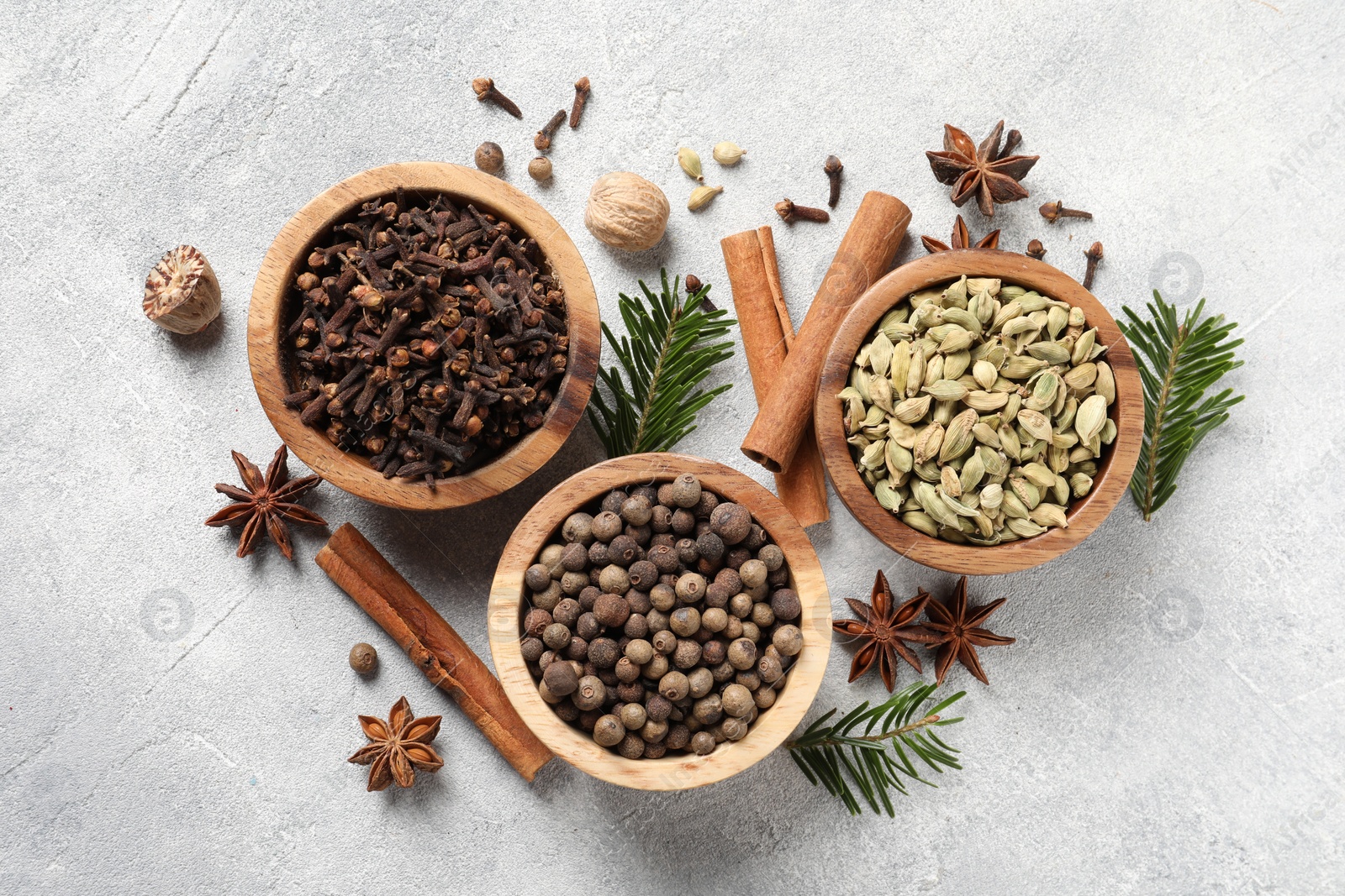 Photo of Different aromatic spices and fir branches on light textured table, flat lay