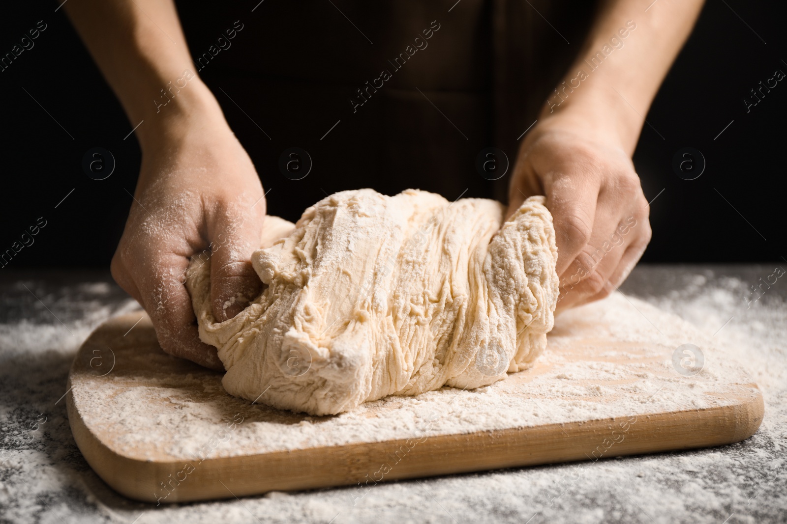 Photo of Woman with dough at grey table, closeup. Making pasta