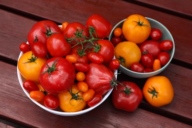 Photo of Bowls with fresh tomatoes on wooden table, above view