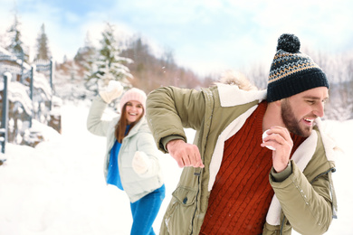 Photo of Happy couple playing snowballs outdoors. Winter vacation