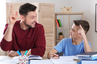 Photo of Dad helping his son with homework in room