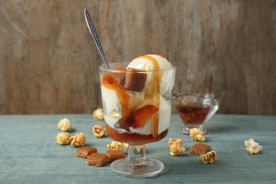 Delicious ice cream with caramel topping in dessert bowl on blue wooden table