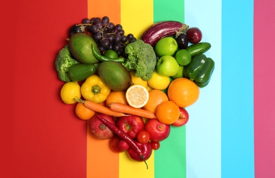 Photo of Rainbow heart made of fruits and vegetables on color background