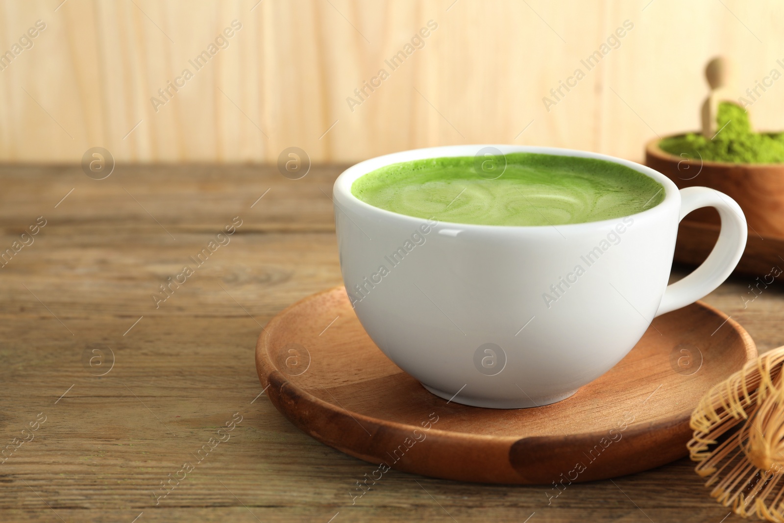 Photo of Cup of fresh matcha latte on wooden table, closeup. Space for text