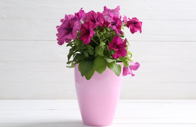 Beautiful pink petunia flowers in plant pot on white wooden table