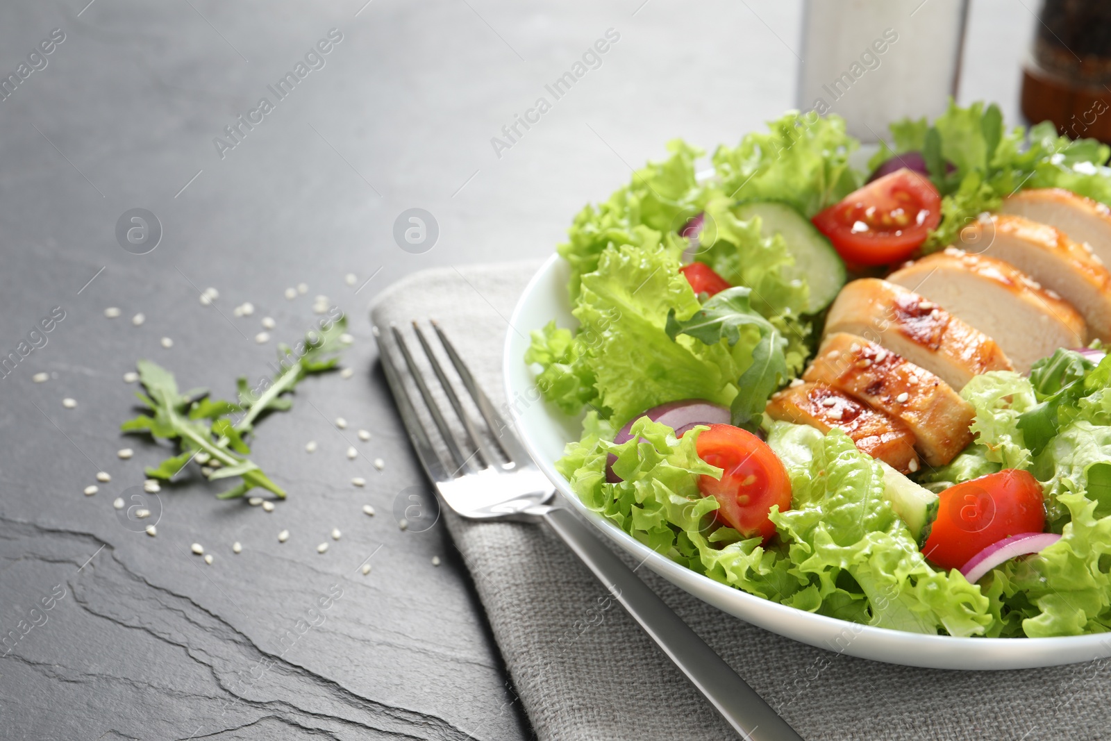 Photo of Delicious salad with chicken and vegetables served on black table, closeup. Space for text