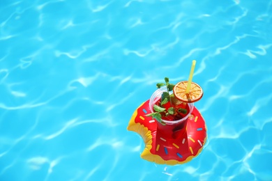 Photo of Inflatable drink holder with cocktail in swimming pool on sunny day. Space for text