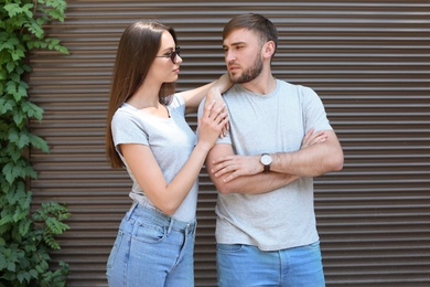 Photo of Young couple wearing gray t-shirts near wall on street.