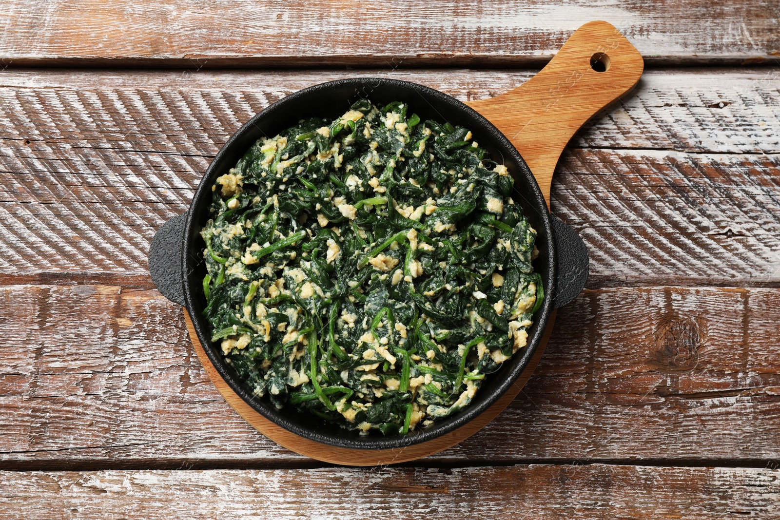 Photo of Tasty spinach dip with eggs in dish on wooden table, top view