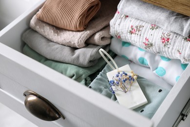 Photo of Beautiful scented wax sachet and clothes in dresser drawer, closeup