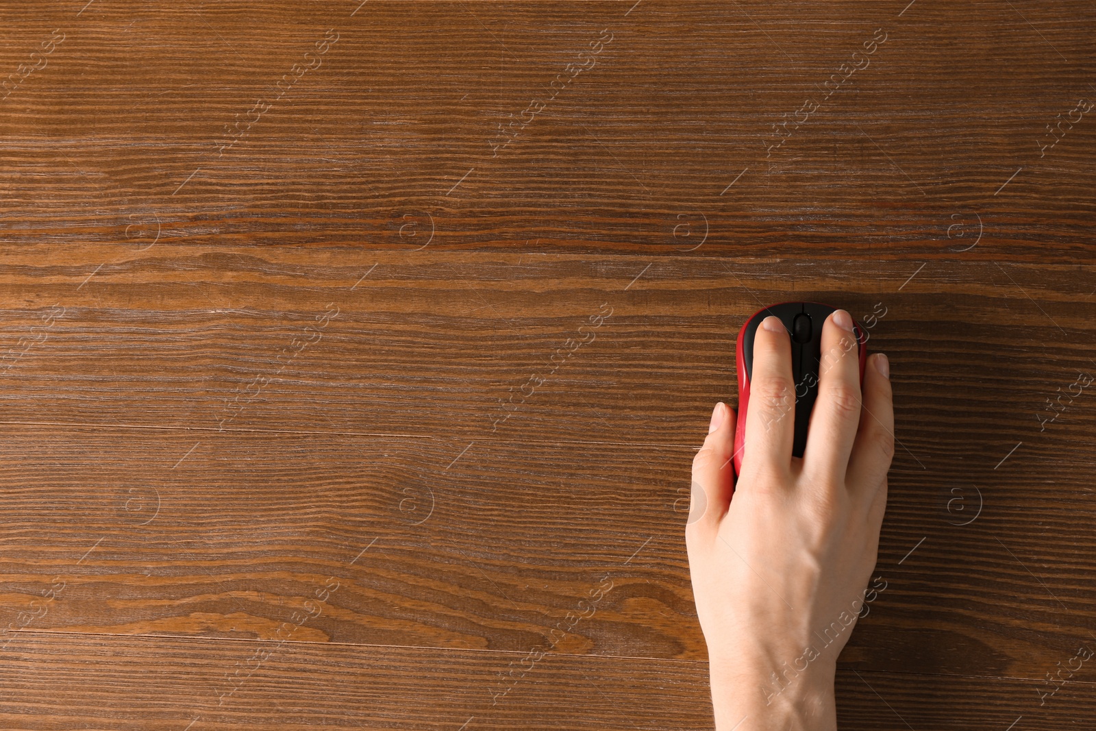 Photo of Woman using computer mouse on wooden background, top view. Space for text