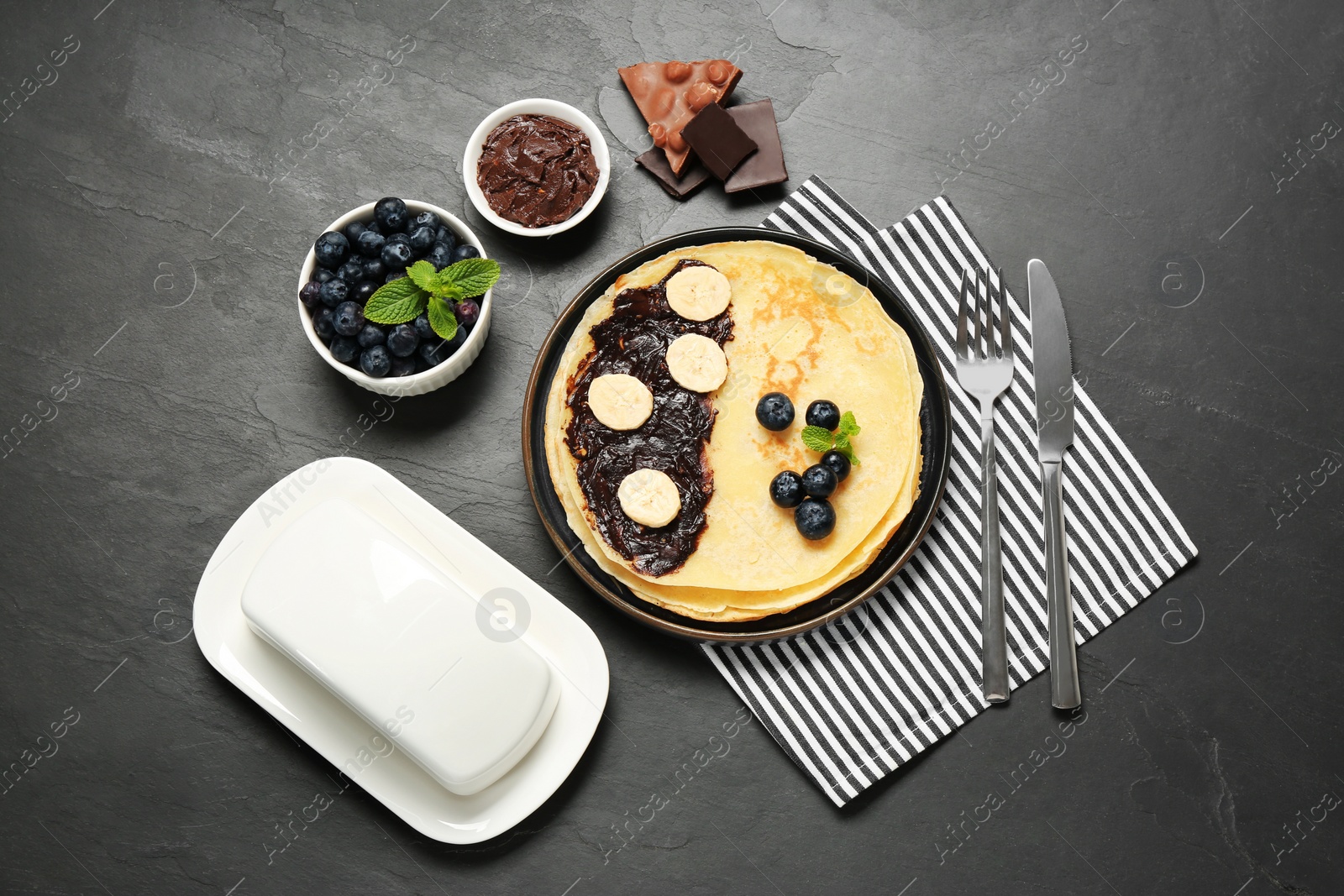 Photo of Delicious crepes with different products served on grey table, flat lay