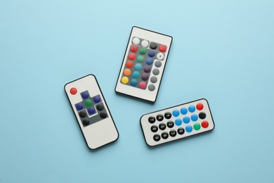 Photo of Different remote controls on light blue background, flat lay