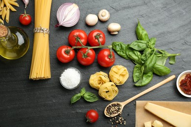 Different types of pasta, spices and products on dark textured table, flat lay