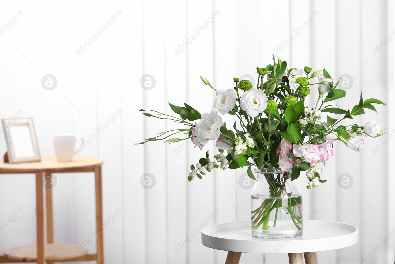 Photo of Glass vase with bouquet of beautiful flowers on table in room. Space for text