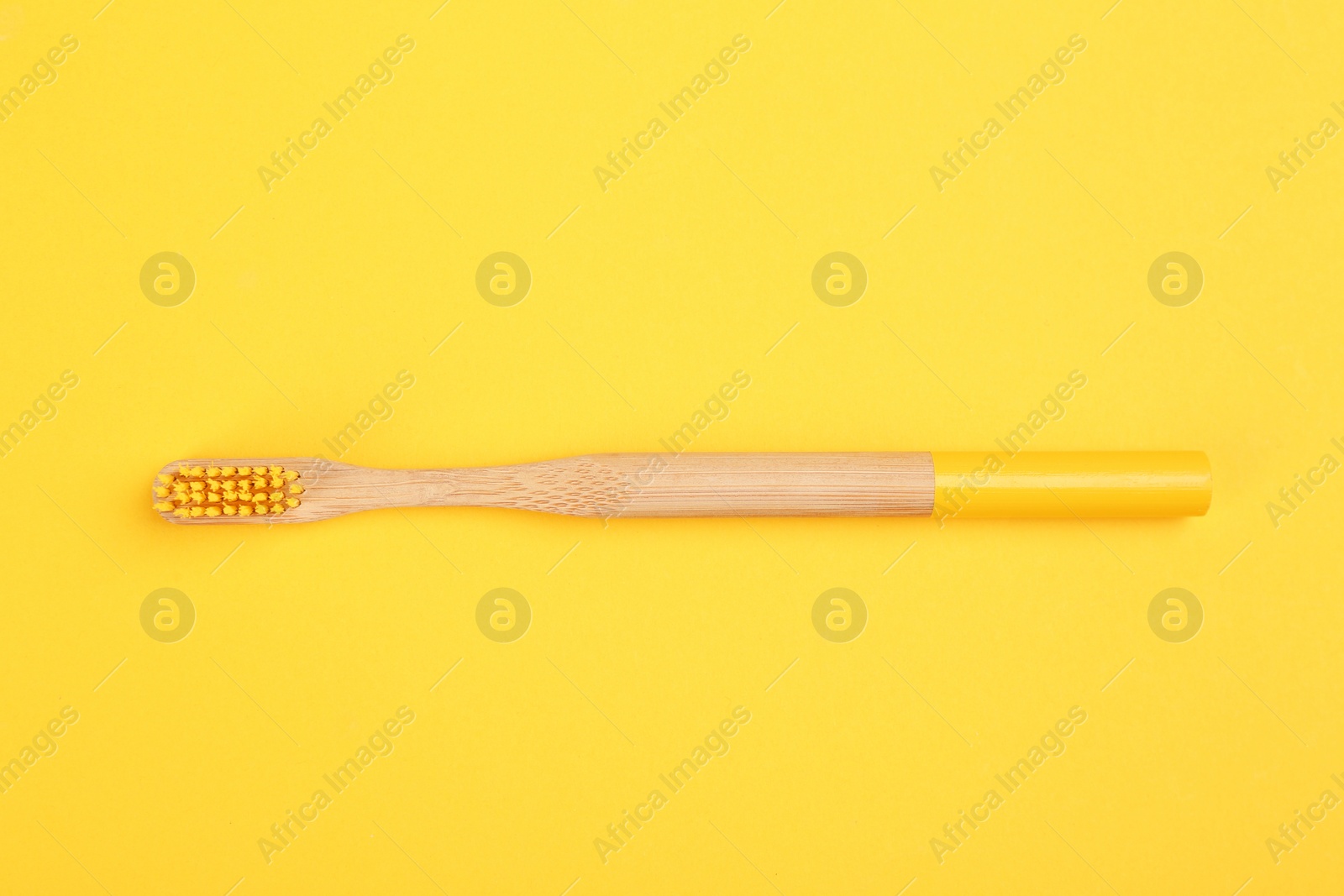 Photo of Toothbrush made of bamboo on yellow background, top view