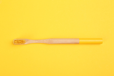 Toothbrush made of bamboo on yellow background, top view