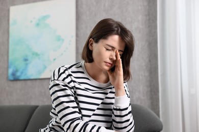 Photo of Overwhelmed woman sitting on sofa at home
