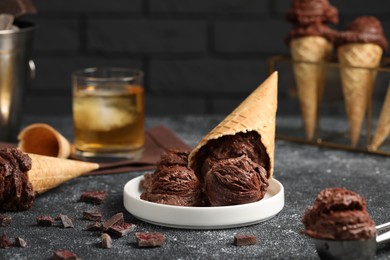 Tasty ice cream scoops, chocolate crumbs and waffle cones on dark textured table, closeup