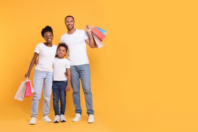 Family shopping. Happy parents and son with colorful bags on orange background, space for text