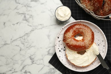 Photo of Delicious bagel with cream cheese on white marble table, flat lay. Space for text